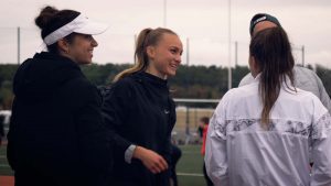 Emilie Girard et d'autres athlètes, discutant et rigolant après une séance d'entraînement sur une piste d'athlétisme.