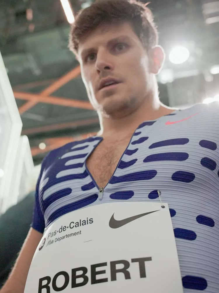 Contre-plongée de Benjamin Robert, en combinaison de compétition Nike Elite 2023, quittant la piste de l'Arena Stade Couvert de Liévin lors du meeting de Liévin 2024 après son 800m.