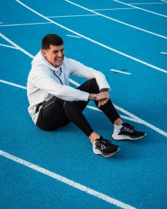 Benjamin Robert, assis sur une piste d'athlétisme en tartan bleu, après une séance d'entrainement avec des Nike Zoom Pegasus 38 aux pieds.