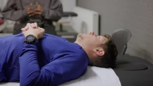 Benjamin Robert, allongé sur le dos, en train de se faire manipuler par un kiné.